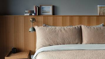 A bedroom with a wooden headboard, a bedside table with a lamp, and a bed with a quilted cover.
