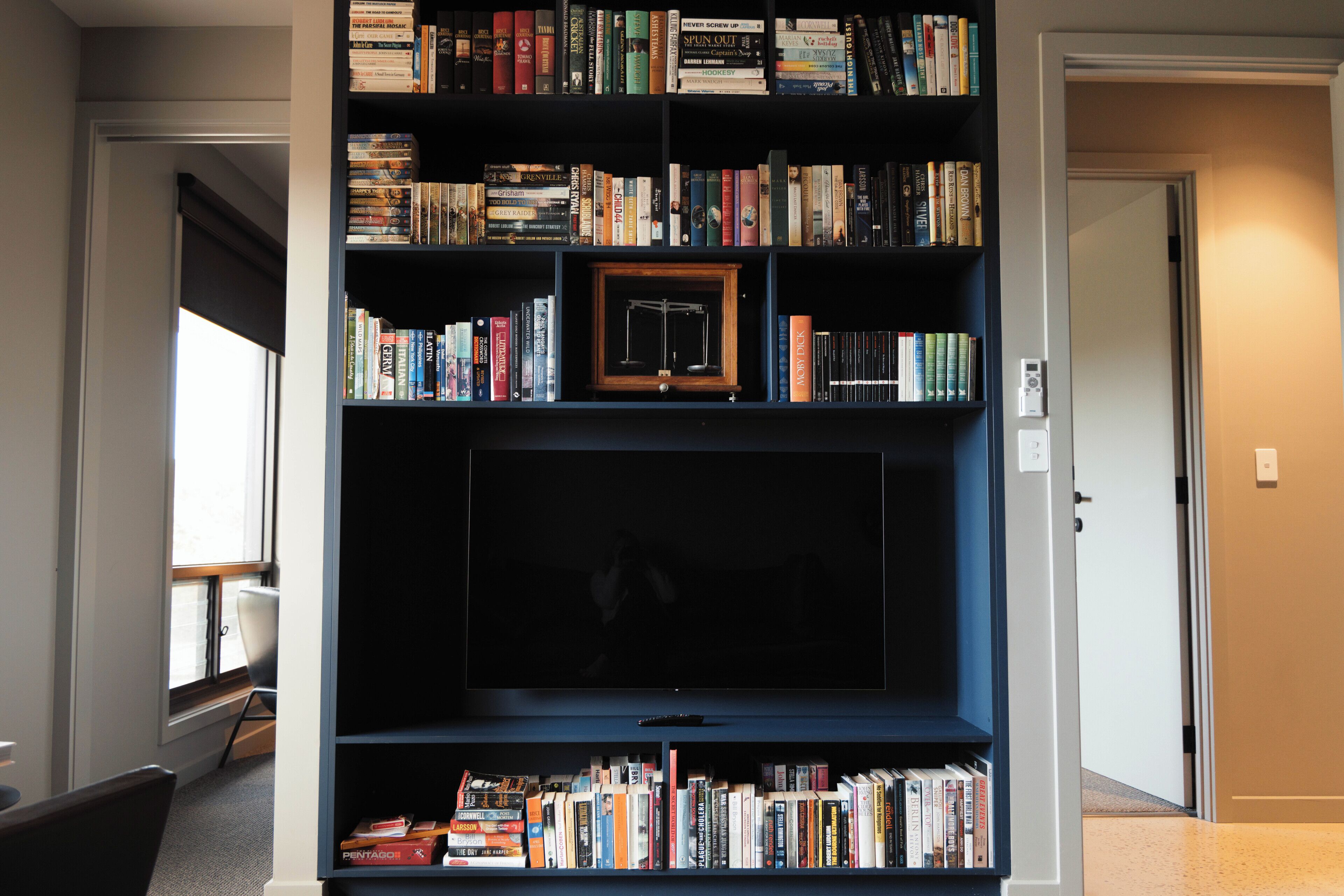 Une bibliothèque remplie de divers ouvrages et un tableau encadré.