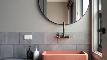 Un baño con un espejo redondo, un lavabo rectangular y un perchero para toallas.