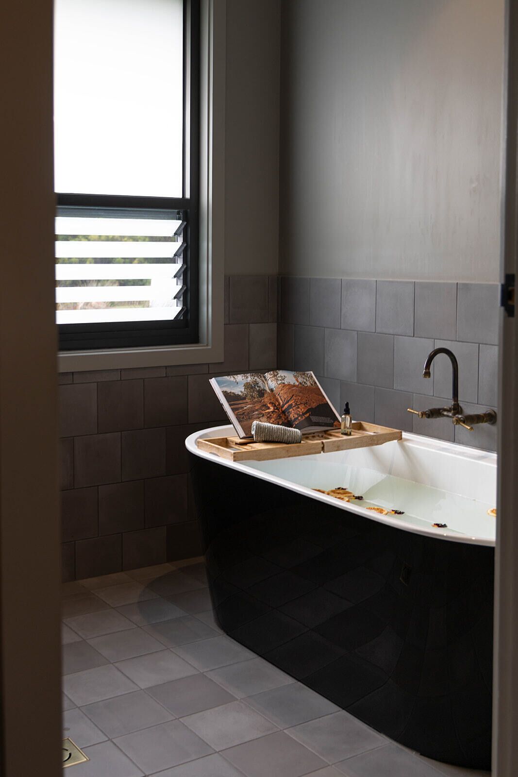 Ein modernes Badezimmer mit einer freistehenden Badewanne, einem Fenster mit Jalousien und einem Handtuchhalter.