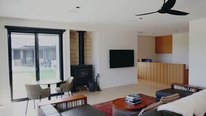 Ein modernes Wohnzimmer mit Kamin, Flachbildfernseher und Essbereich mit Tisch und Stühlen.