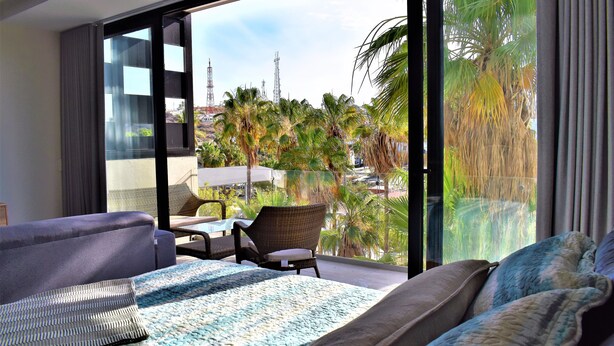 A modern hotel room with a large balcony, a sofa, a chair, and a bed. - Intimate & Bright Studio w/ Rooftop Pool in the Art District San Jose Del Cabo (San José del Cabo)