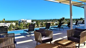 A poolside area with wicker furniture, a view of the ocean, and a clear blue sky. - Intimate & Bright Studio w/ Rooftop Pool in the Art District San Jose Del Cabo (San José del Cabo)