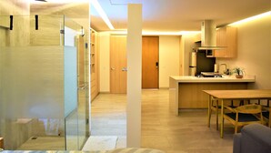 A modern kitchen with a wooden countertop, a built-in stove, and a sink. There is a dining area with a wooden table and chairs. - Intimate & Bright Studio w/ Rooftop Pool in the Art District San Jose Del Cabo (San José del Cabo)