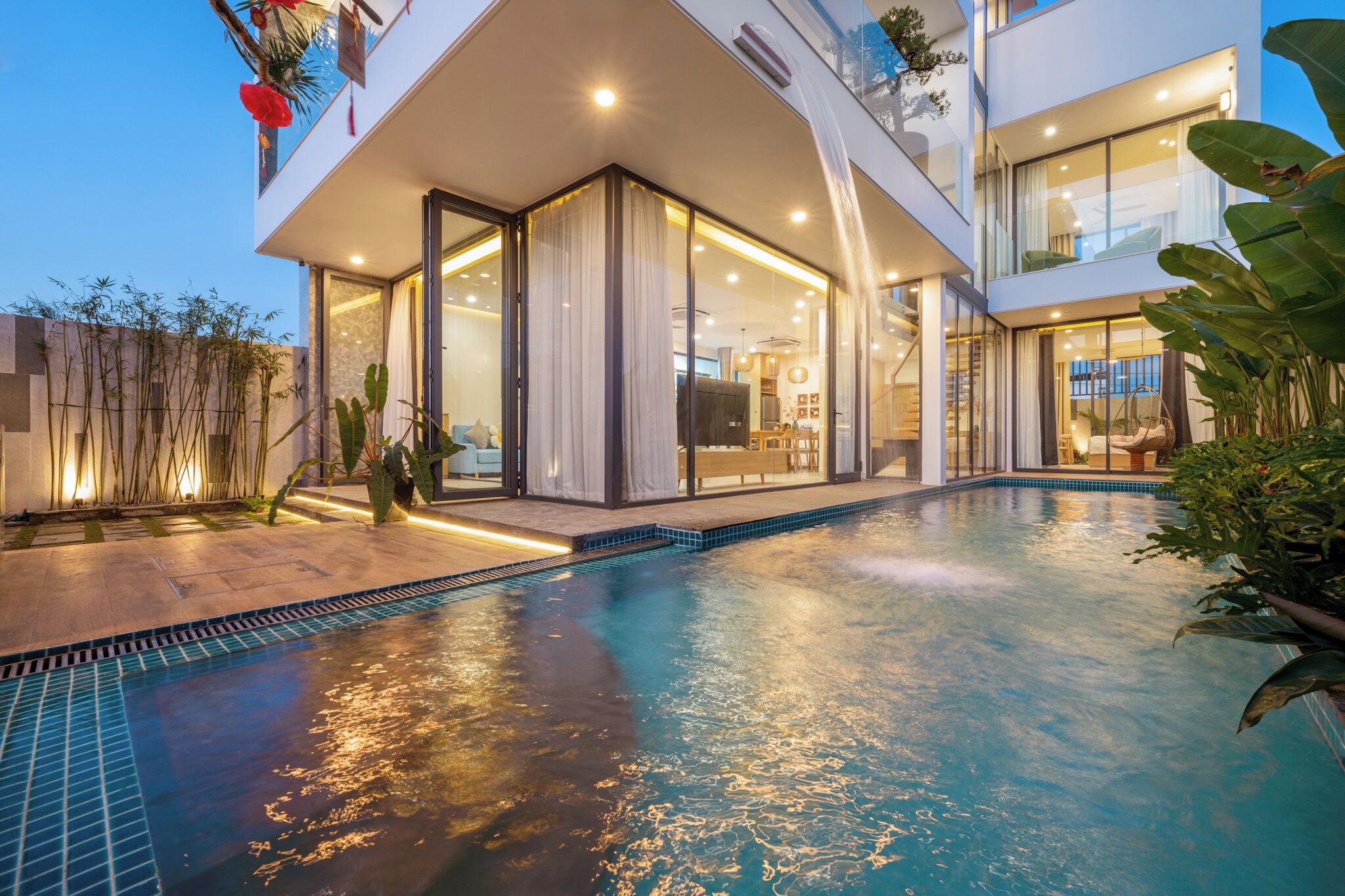 Ein modernes Haus mit Swimmingpool, großen Glasfenstern und einem hellen Innenraum.