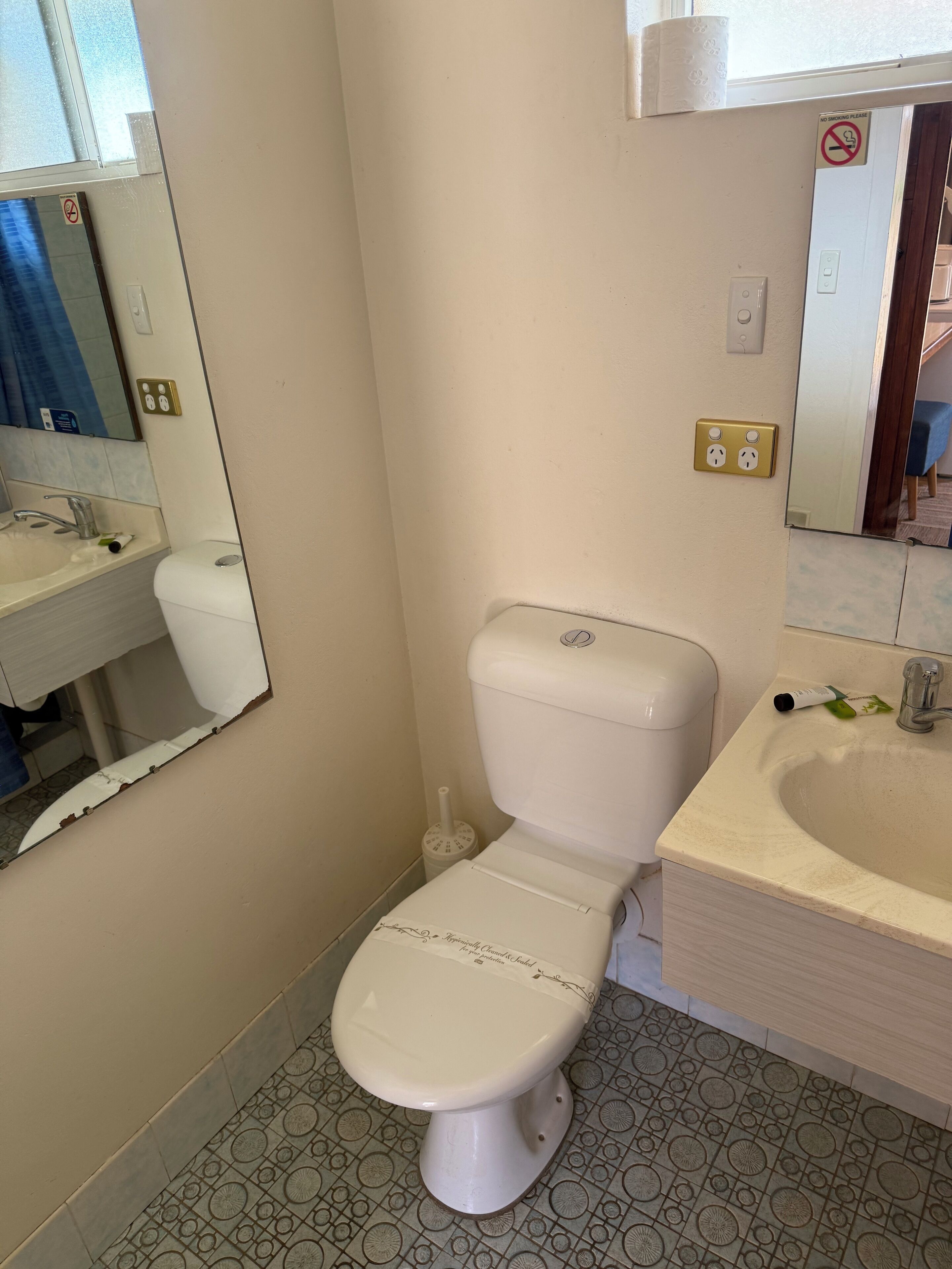 Une salle de bain avec des toilettes, un lavabo et un miroir.