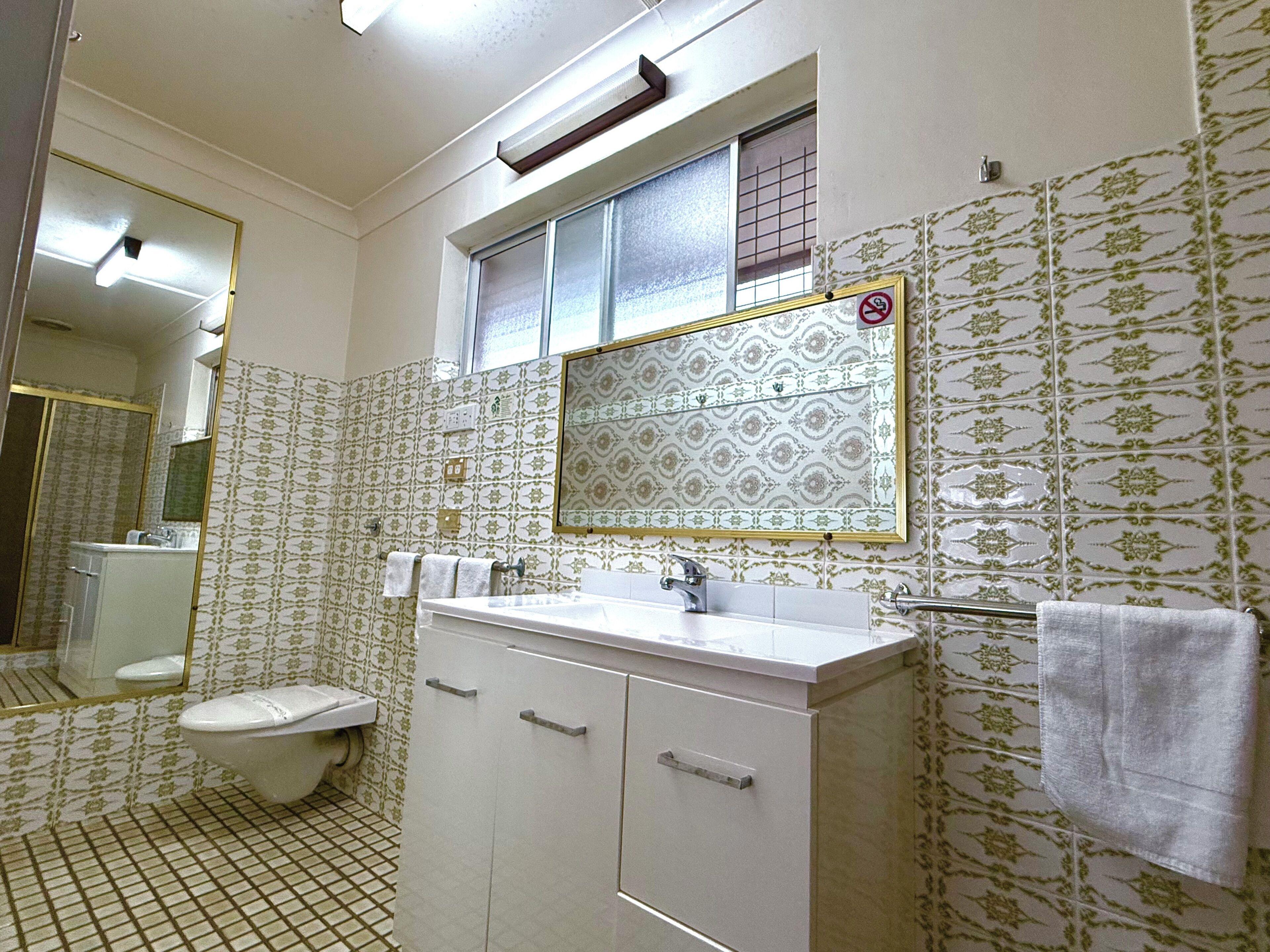 A bathroom with a toilet, sink, and mirror.