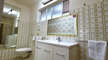 A bathroom with a toilet, sink, and mirror.