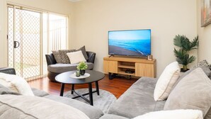 A living room with a sofa, a coffee table, a TV, and a sliding glass door.