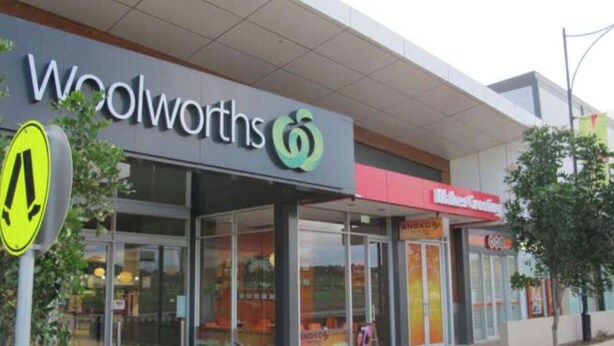 A Woolworths store with a clear pedestrian crossing sign, large glass windows, and a visible entrance.