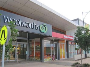 Uma loja Woolworths com uma faixa de pedestres bem visível, grandes janelas de vidro e entrada aparente.