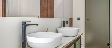 A modern bathroom with a large mirror, two sinks, and a door.