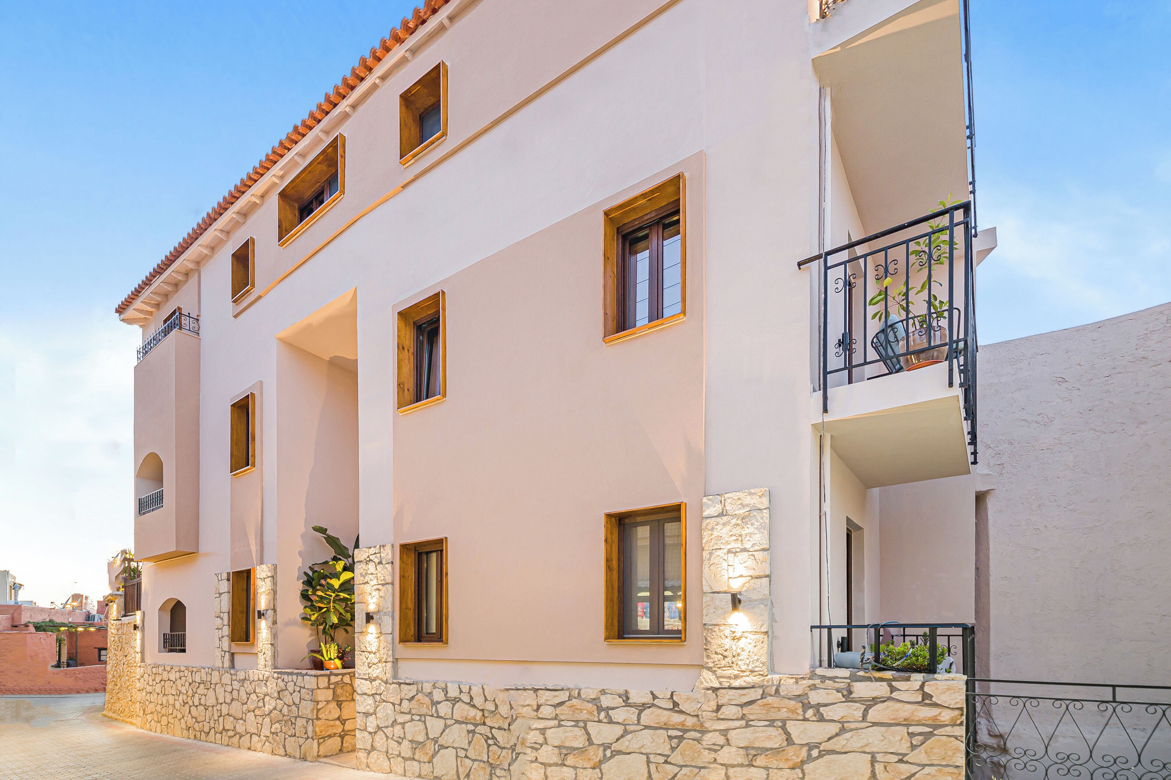 A multi-story building with balconies, stone foundation, and multiple windows.