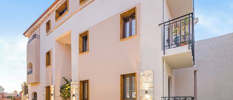 A multi-story building with balconies, stone foundation, and multiple windows.
