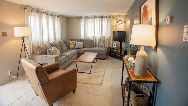 A modern living room with a sofa, armchair, coffee table, and a TV.
