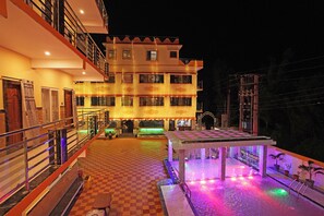 A hotel with a checkered floor, a balcony with railings, and a pool area with colorful lights. - HOTEL DREAM BASANTI (Kanthi)