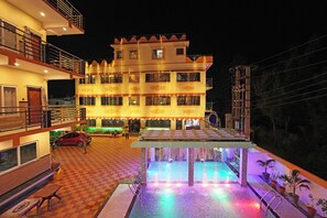 A multi-story hotel with a pool area featuring colorful lighting. - HOTEL DREAM BASANTI (Kanthi)