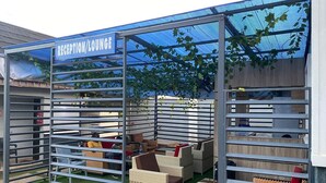 A reception lounge with a metal partition, wicker furniture, and a blue canopy. - Geoworld Apartments & Suites (Makurdi)