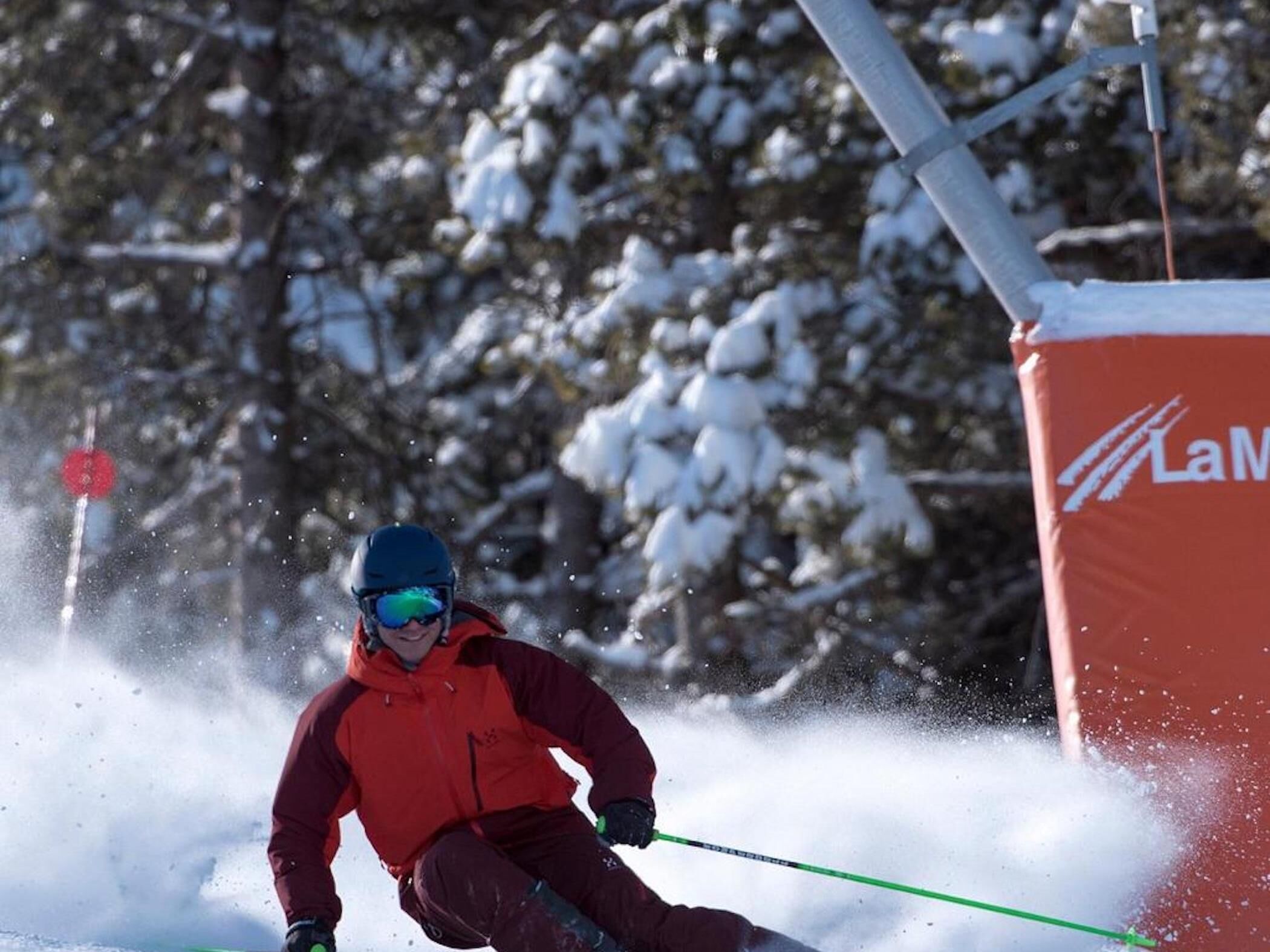 A person skiing on a snowy slope with a red and black jacket, a blue helmet, and goggles.