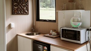Una cocina compacta con un lavamanos, un microondas y una ventana con vistas a la vegetación.