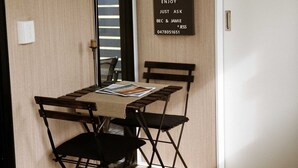 Una habitación con suelo de madera, una mesa con sillas, una puerta y un letrero de bienvenida.