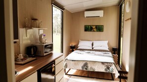 Un dormitorio pequeño con cama, mesitas de noche, microondas y ventana.