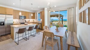 Una cocina moderna con una isla central, taburetes de bar y una mesa de comedor con sillas.