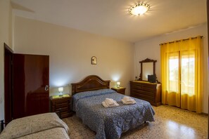 A bedroom with a bed, bedside tables, a dresser, a mirror, and a window with curtains.