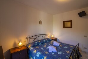 Une chambre à coucher comprenant un lit, deux tables de chevet, un téléviseur fixé au mur et un petit objet décoratif placé au-dessus du lit.
