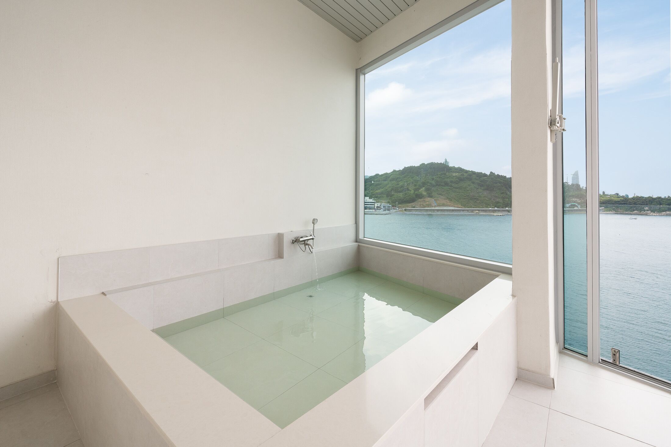 Un baño moderno con una bañera grande, vistas al mar y un balcón.