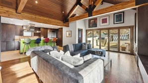 Un intérieur moderne avec un plafond en bois, un canapé, un coin repas et une vue dégagée grâce à de grandes portes vitrées.