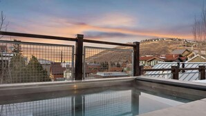 Une piscine offrant une vue sur un paysage vallonné et des immeubles résidentiels.