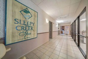 A hallway with a sign for Sleepy Creek Spa, a reception area, and a view of the spa facilities.