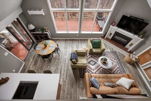 A spacious living room with a large window, a fireplace, a TV, and a cozy seating area. - Fireplace, Fire Pit, Deck, WiFi & Pool Access (Hedgesville)