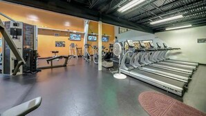 Un gimnasio con cintas de correr, bicicletas estáticas y máquinas de pesas.