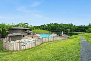 Un jardin avec une piscine, une terrasse en bois et une maison.