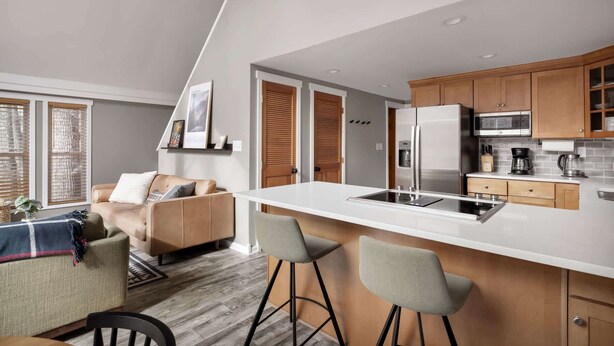 Una cocina moderna con una isla central, armarios de madera y electrodomésticos de acero inoxidable.