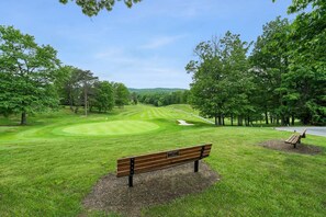 A golf course with a bench in the foreground and a road in the background. - Fireplace, Fire Pit, Deck, WiFi & Pool Access (Hedgesville)