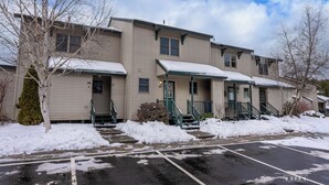 A multi-story residential building with a snow-covered roof and steps.