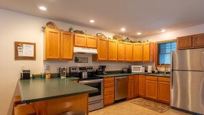 A kitchen with wooden cabinets, a stainless steel refrigerator, a microwave, and a stove.