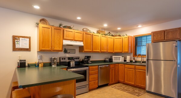 A kitchen with wooden cabinets, a stainless steel refrigerator, a microwave, and a stove. - Pine Hill #23 | Phase 2 (Lake Placid)