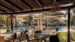 Area esterna con tavoli e sedie, una piscina e vista su un edificio residenziale.