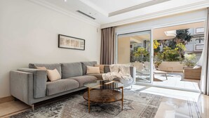 Un soggiorno moderno con un divano grigio, un tavolino in vetro e un tappeto decorato.