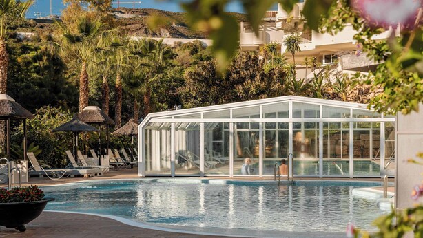Una piscina con lettini e zona vetrata.