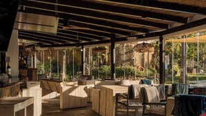 Un'ampia zona relax all'aperto con mobili in legno e pavimento in pietra, con vista su un rigoglioso giardino.