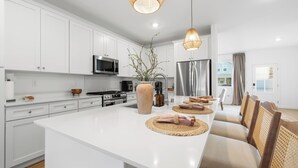 Una cocina moderna con armarios blancos, electrodomésticos de acero inoxidable y una isla central con asientos.