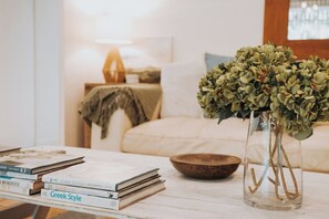 A living room with a white sofa, a coffee table with books and a vase of green foliage, and a lamp in the background. - “ Everest” - One of Maleny's best-kept secrets (Maleny)