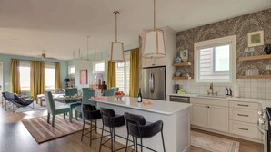 A modern kitchen with a central island, bar stools, and pendant lighting. - Lyric | Luxury Stay with Rooftop & Firepit (Nashville)