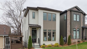 A modern two-story house with a front porch, a small deck, and a well-maintained lawn. - Lyric | Luxury Stay with Rooftop & Firepit (Nashville)