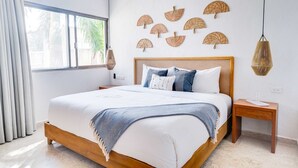 Une chambre à coucher avec un grand lit, une table de chevet, une lampe suspendue et des œuvres d’art murales.